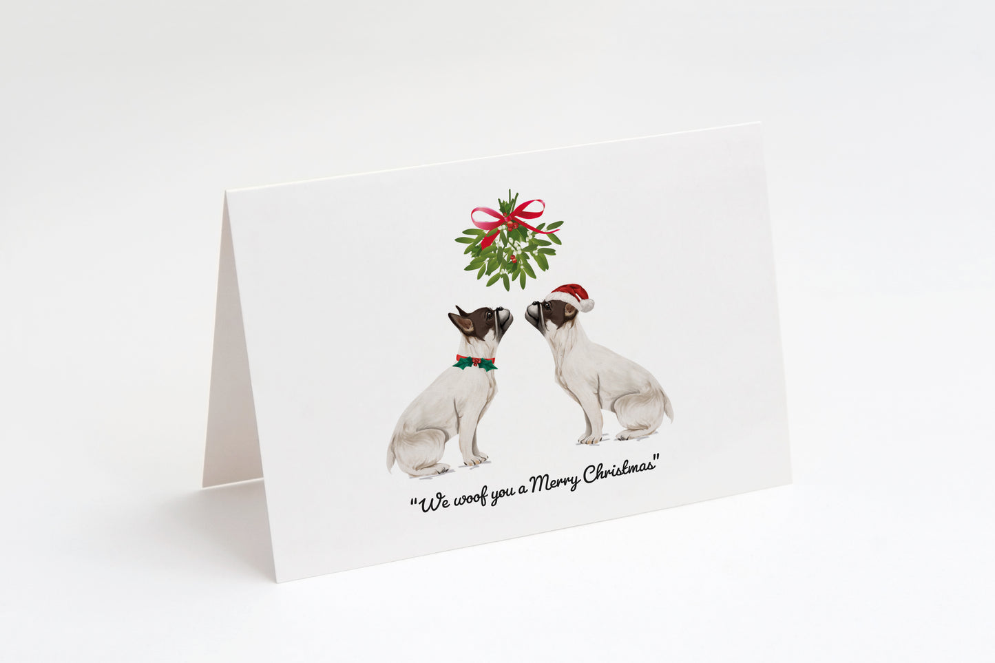Christmas card with two white French Bulldogs and a wreath on a white background. "We woof you a Merry Christmas!" text underneath.