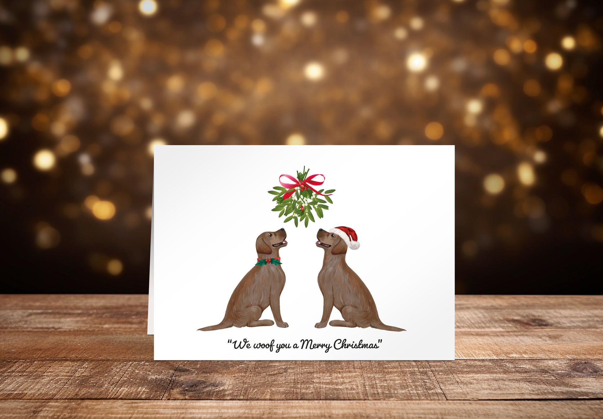 Christmas card with two brown Labrador dogs sitting underneath a mistletoe wreath on a white background, with the text: "We woof you a Merry Christmas"