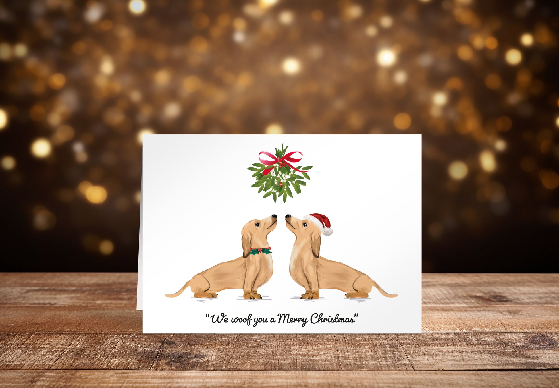 Christmas card with two cream Dachshund dogs underneath mistletoe on a white background with the text "We woof you a Merry Christmas" underneath. 